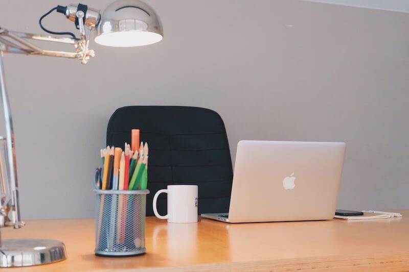 escritorio con MacBook bote lápices taza