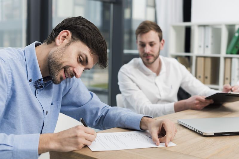 hombres firmando contratos